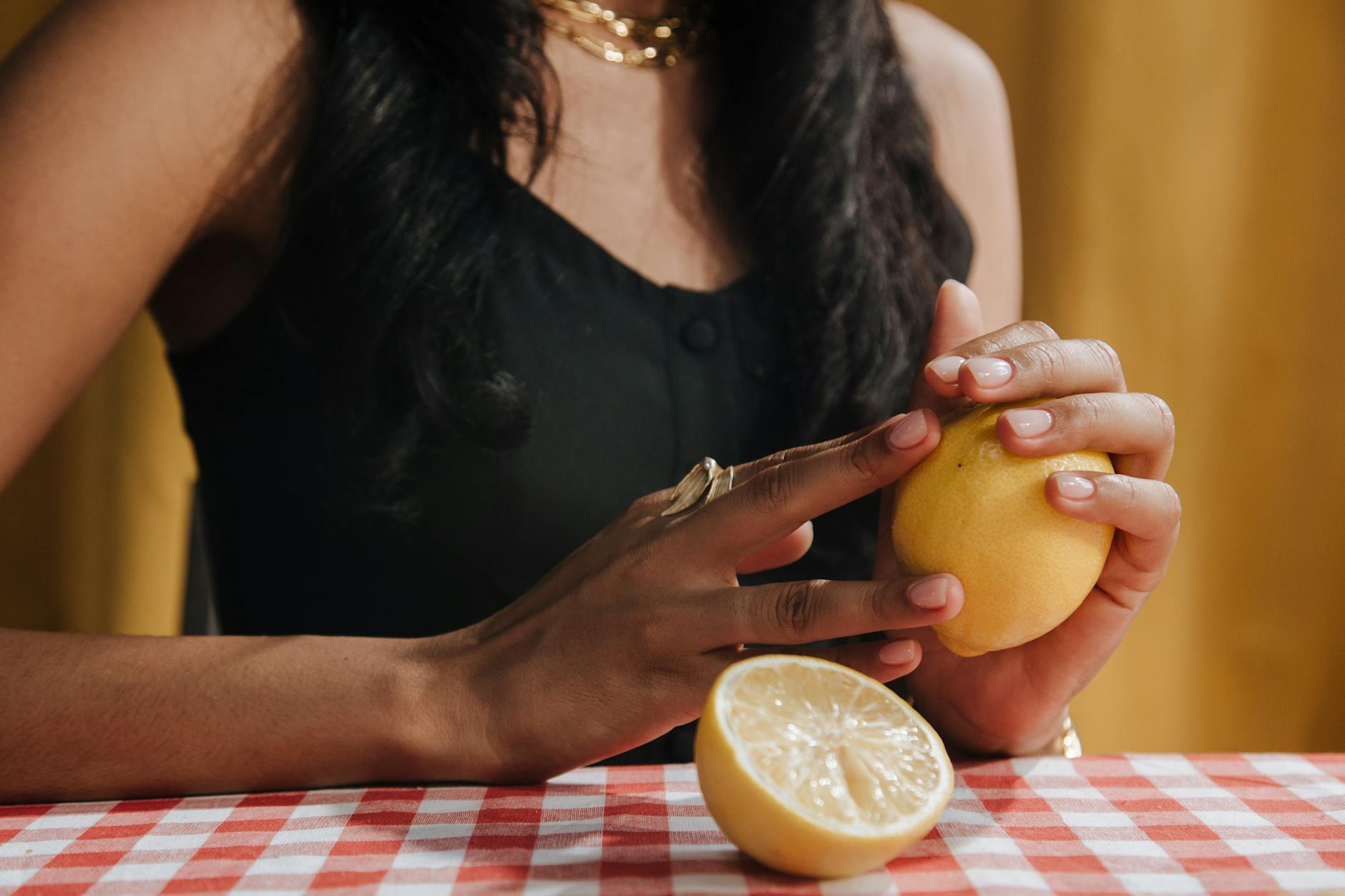 A bright yellow silicone clitoral vibrator surrounded by fresh fruit on a yellow background
