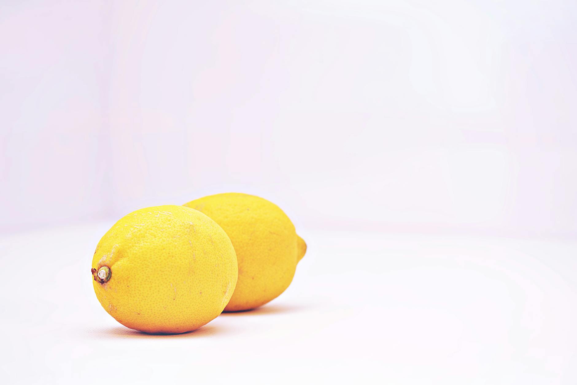 Two bright lemons on a minimalist white background, symbolizing the citrus-inspired design of lemon clitoral vibrators