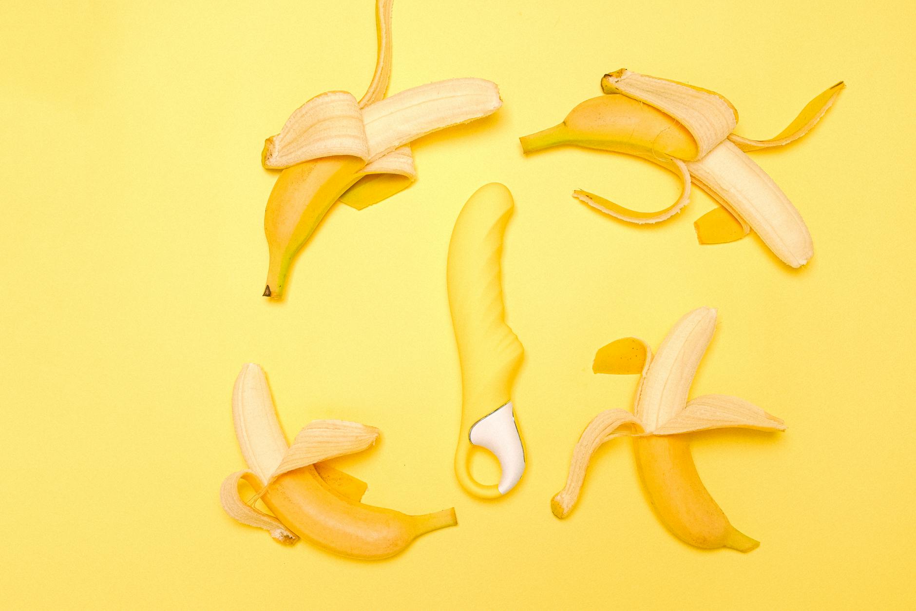Yellow lemon clitoral vibrator surrounded by fresh lemons on yellow background