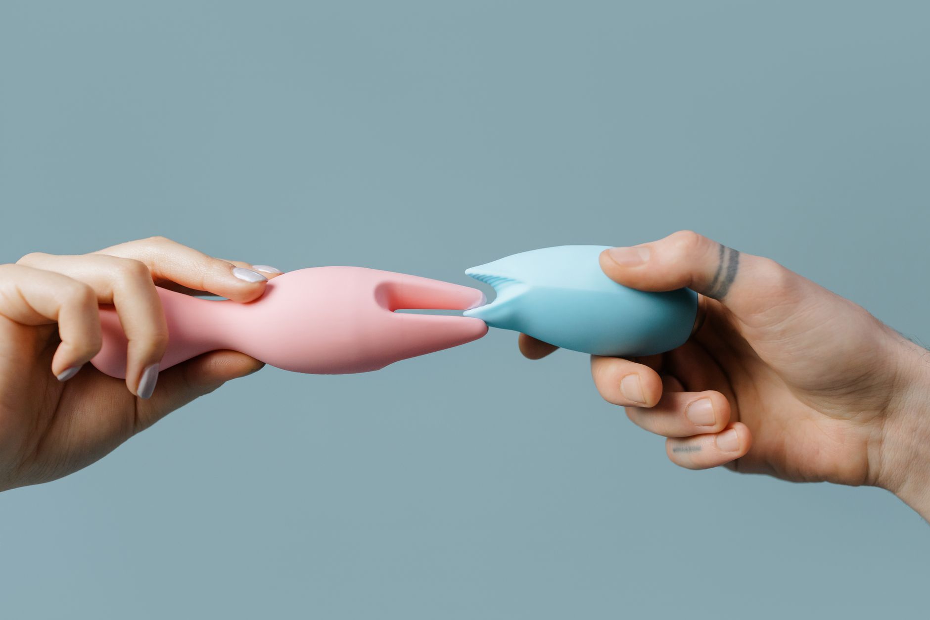 Hands holding pastel-colored silicone toys, perfect for shared intimate moments