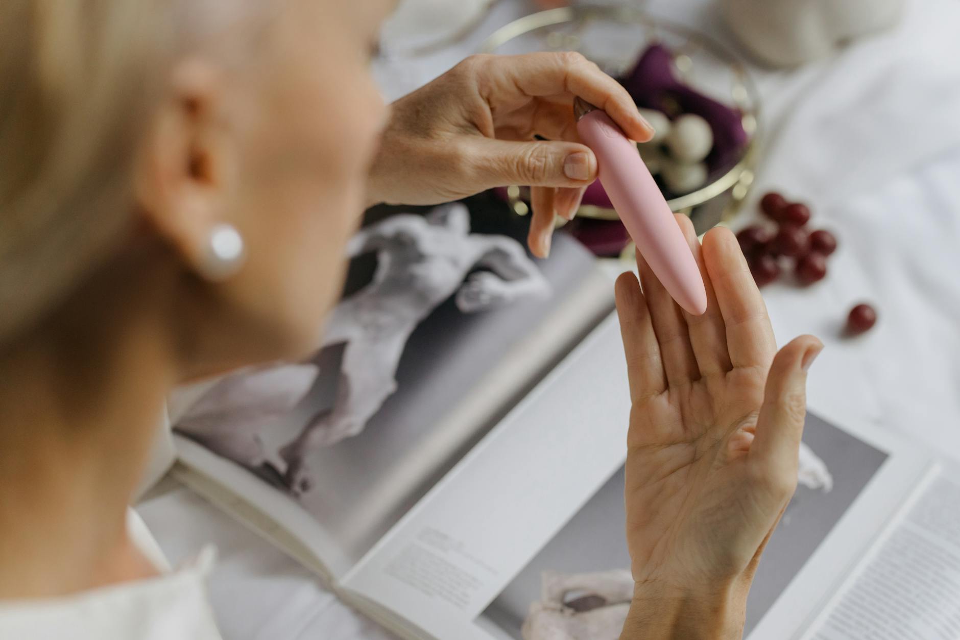 Close-up of hands holding a pink personal vibrator, with soft lighting emphasizing intimate self-connection.