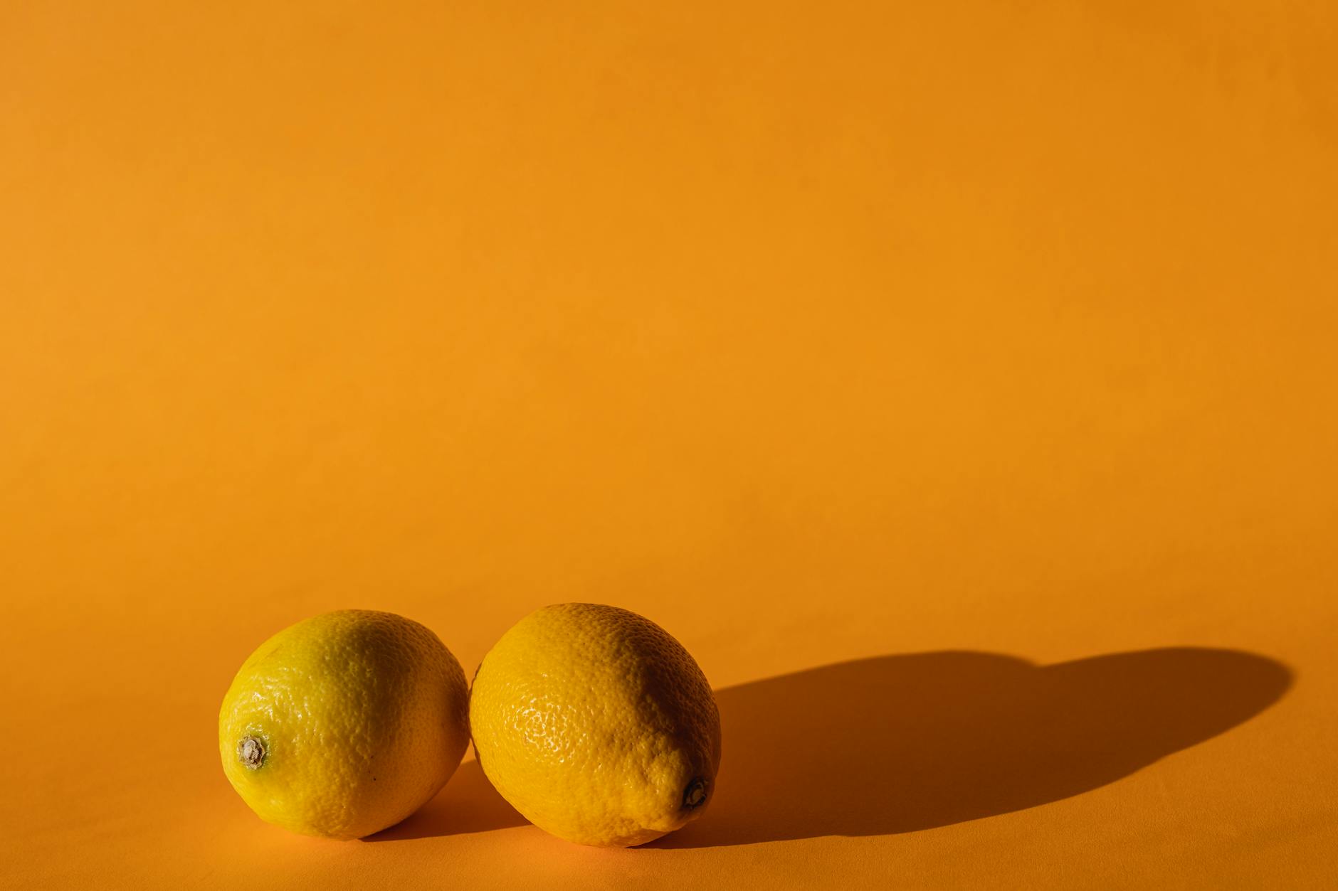 Ripe lemons on a bright yellow background, representing the gentle sensation of lemon vibrators